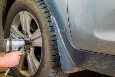 Büyük araba tekerleğini pnömatik bir anahtarla sökmek.