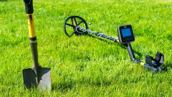 Metal detector lying on the grass. Treasure hunt.