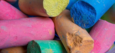 Renkli tebeşirler beyaz bir arkaplan üzerinde çapraz olarak düzenlenmiştir