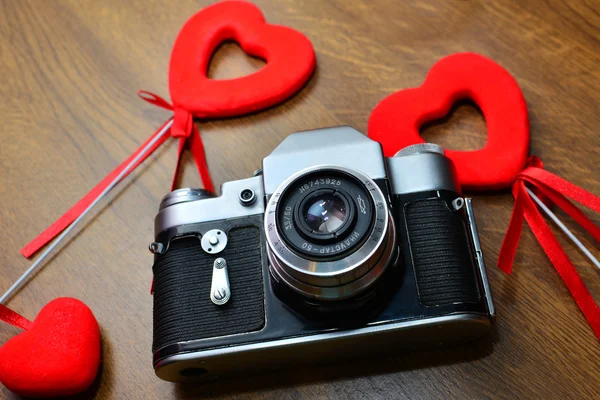 Vintage kamera a fából készült asztal piros szívek — Stock Fotó