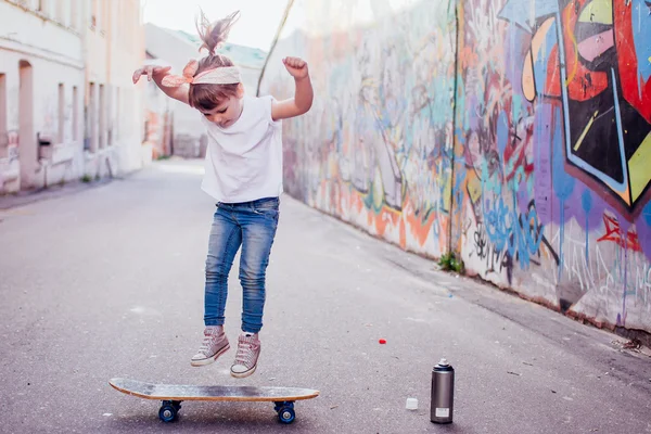 Jeune patineuse près du mur de graffiti — Photo