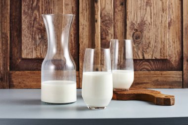 Şişe ve iki bardak süt, ahşap bir masada..