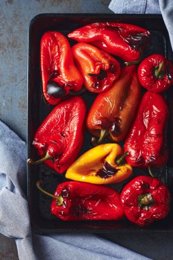 Koyu bir arka planda kavrulmuş kırmızı ve sarı biberli fırın tepsisi. Üst görünüm.