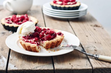 Kırsal ahşap bir masada ahududu ile pişirilmiş mini tartlar.