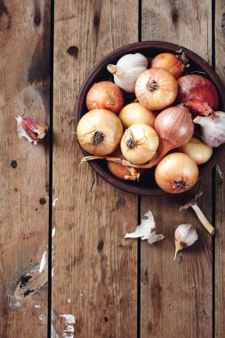 Sarı, kırmızı soğan ve sarımsak ahşap arka planda bir kasede.