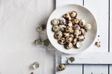 Beyaz bir masanın üstünde kasede bıldırcın yumurtası..