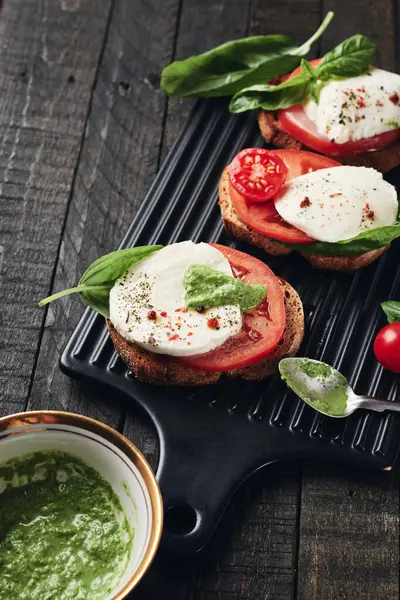 Açık sandviç veya mozzarella peynirli bruschetta, domates ve fesleğen, koyu ahşap arka planda Caprese..