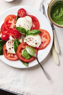 Caprese salatası. Domates, mozarella peyniri, fesleğen yaprağı ve pesto sosu..