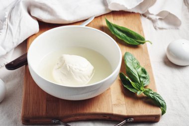 Kase içinde Mozzarella peyniri topu ve taze fesleğen yaprakları..