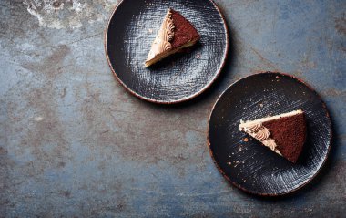 İki dilim çikolatalı kek, siyah tabakta, en üstte..