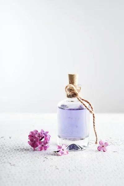 Perfume bottle and purple lilac flowers. Perfumery and cosmetics concept.