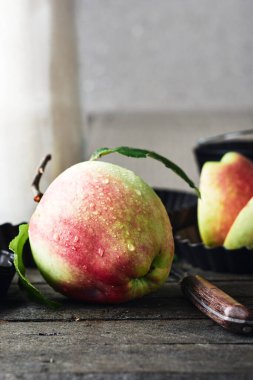 Red apple with water drops on a wooden kitchen table.