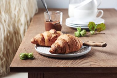 Two croissants with chocolate cream and hazelnuts on a wooden table.
