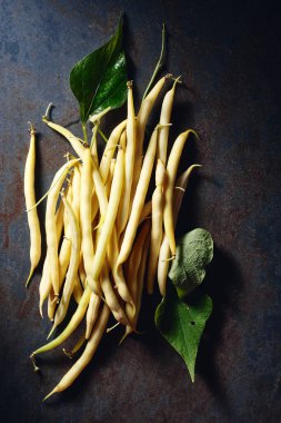 Yellow wax beans on a dark blue background, top view.