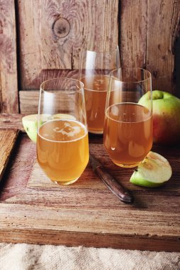 Three glasses of apple drink, cider on a wooden background.