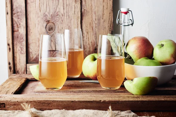 Three glasses of apple drink, cider on a wooden background.