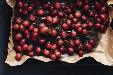 Fırında kızartılmış kırmızı üzüm. Koyu arkaplan, üst görünüm.