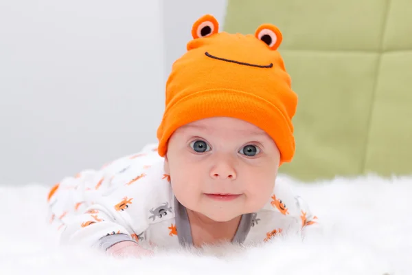 Bebé acostado en una piel blanca con gorra naranja — Foto de Stock