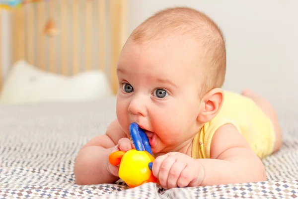 Baby lügt und nagt an Spielzeug — Stockfoto