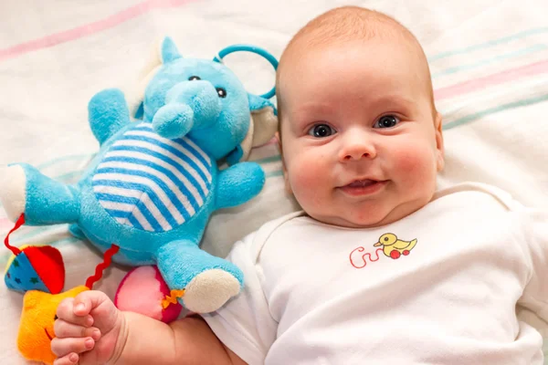 Bebê encontra-se com brinquedo elefante azul — Fotografia de Stock