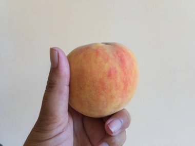Holding a peach fruit in hand