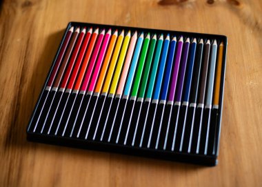 Ahşap masadaki bir paketin içindeki renkli kalemler..