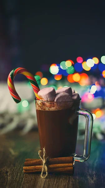 Soğuk kış mevsimi bardağı sıcak çikolata ve tarçın çubuklu marşmelov ve şeker kamışlı anason (anason) ve parlak renkli bulanık noel ışıkları