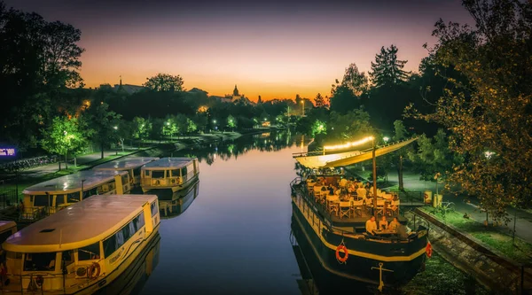 Romanya ve Timisoara kanalı Bega nehrinde gece şehir fotoğrafçılığı tekneleri