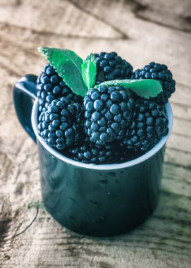 Taze böğürtlen ve ahşap masa üzerinde nane yaprakları.