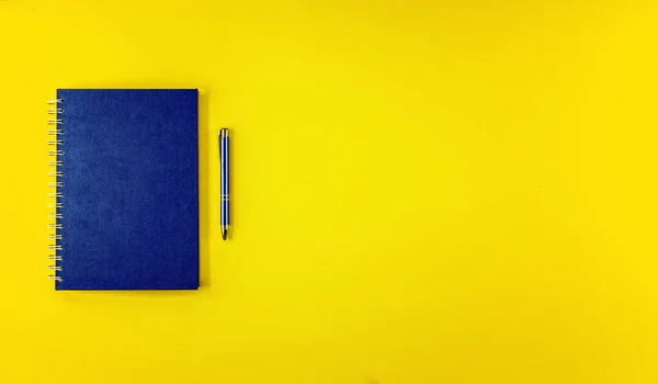 Sarı arka planda tükenmez kalemle düz görünüm mavi defter gündemi yatıyordu