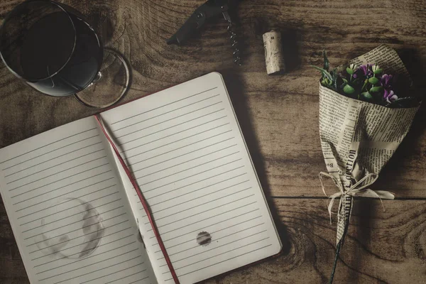 Gazete retro görünümlü kırmızı şarap ve çiçekli düz bir defter günlüğü.