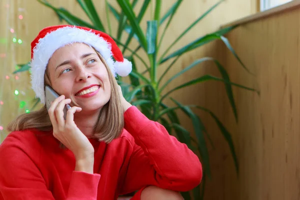 Celebration in self-isolation. christmas online congratulations: a woman in red Santa hats using a tablet, smartphone. Winter holidays