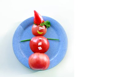 Bir tabak domates, biber, jambon ve ottan oluşan kardan adam. Yemekten Noel dekorasyonu. Beyaz bir arka planda izole edilmiş. Boşluğu kopyala
