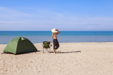 Denize yolculuk. Sahilde kamp yapmak. Deniz kenarında bir tatil. Erkekler ve kumda turist koltuğu olan bir çadır.