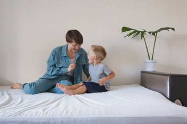 Gündelik hayatta modern teknolojiler bir kadın ve çocuk yataktaki tablete bakar. Aletlerle hobiler ve eğlence. Aile tatili, anne ve oğlu evde birlikte vakit geçirmek. Anne sevgisi.