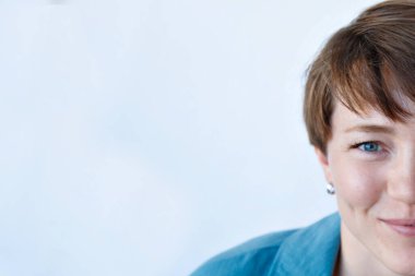 Mavi elbiseli, güzel, mutlu, gülümseyen bir kadının portresi, beyaz arka plan. yarım yüz