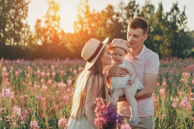 Mutlu bir aile bir çiçek çayırında yürüyor. Aşk ve bahar çiçek açıyor.
