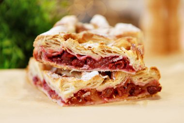 Yemek masasında bir parça vişneli turta. Yemek yemek için hazır. Puf böreği. Yemek pişirmek için mutfak aletleri