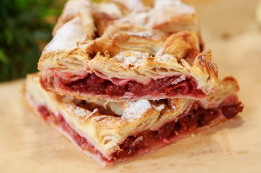 Yemek masasında bir parça vişneli turta. Yemek yemek için hazır. Puf böreği. Yemek pişirmek için mutfak aletleri