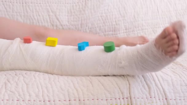 Jambe Cassée Gros Plan Plâtre Sur Les Pieds Jouets Colorés — Video