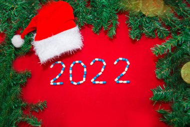 Coronavirus, ncov-19 ve yeni yıl. Kendini izole bir tatil, hastane. Noel süsleri, tıbbi aletler şırınga ve Noel Baba şapkası. Kırmızı arkaplanda boşluk kopyala