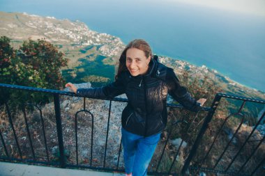 Sırt çantalı bir kız aydınlığın kenarında duruyor. Dağları aşın