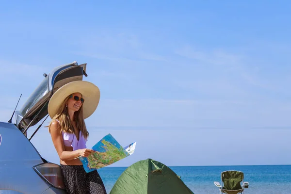 travel to the sea by car. the girl is looking for a road on the map. the car stopped on the beach