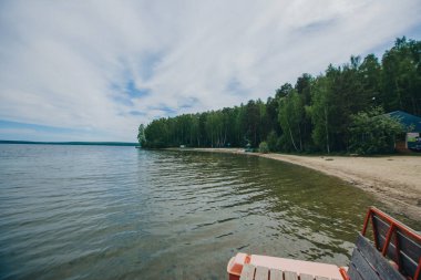 Hava gözlemi konsepti, meteoroloji. Rüzgar ve küçük dalgalar. Nehir manzarası, ağaçlar ve kumlu sahil.