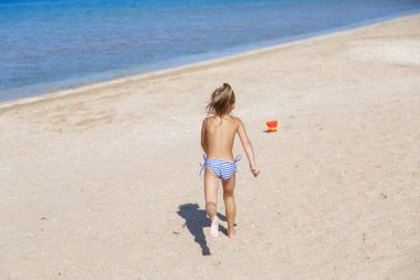 Turizm sezonu: bir çocuk sahilde yürür. Deniz kenarında tatil
