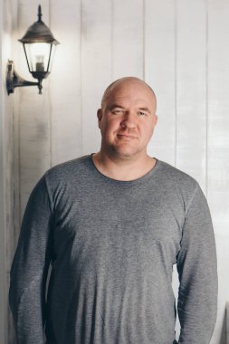 Beyaz arka planda gri elbiseli kel yakışıklı adam.