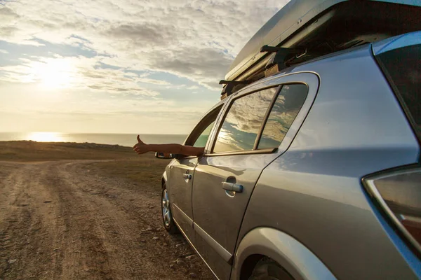 travel to the sea by car. the girl stuck out her hand. thumb as a sign of pleasure