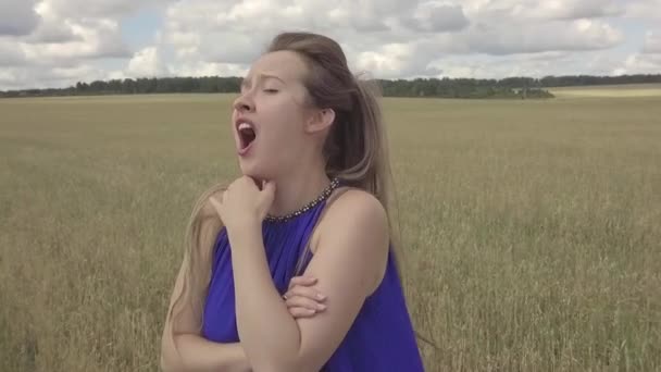青いドレスの女の子が畑で悲しい歌を歌う 自然の中で歌う クリップを屋外で撮影します 顔を閉じて — ストック動画