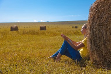 Bir kız samanlıkta güneşleniyor. Köy hayatı: Kış için saman biçmek. hayvan yemi.