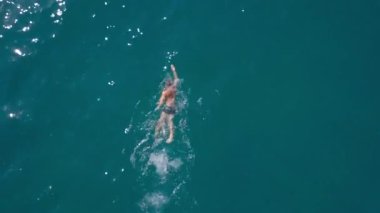 İnsansız hava aracının görüntüsü: Denizde sürünen bir adam. Suda bir yüzücü. Okyanus manzarası.